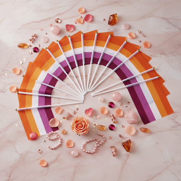 Fan of hand-held sunset lesbian pride flags arranged on a marble surface