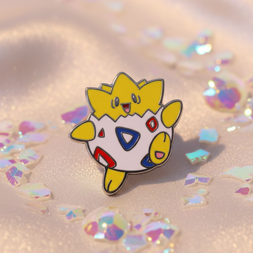 Togepi enamel pin with yellow and white character design on iridescent fabric