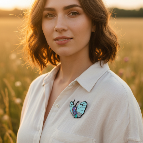 Butterfly enamel pin with blue wings on a white shirt in a sunlit field