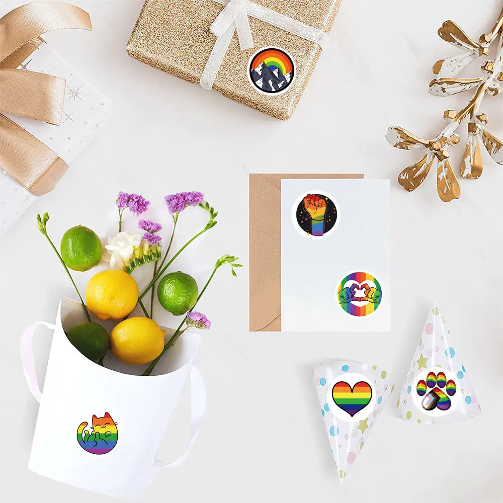 Overhead display of Pride stickers decorating gifts, a card, a bouquet, and party hats