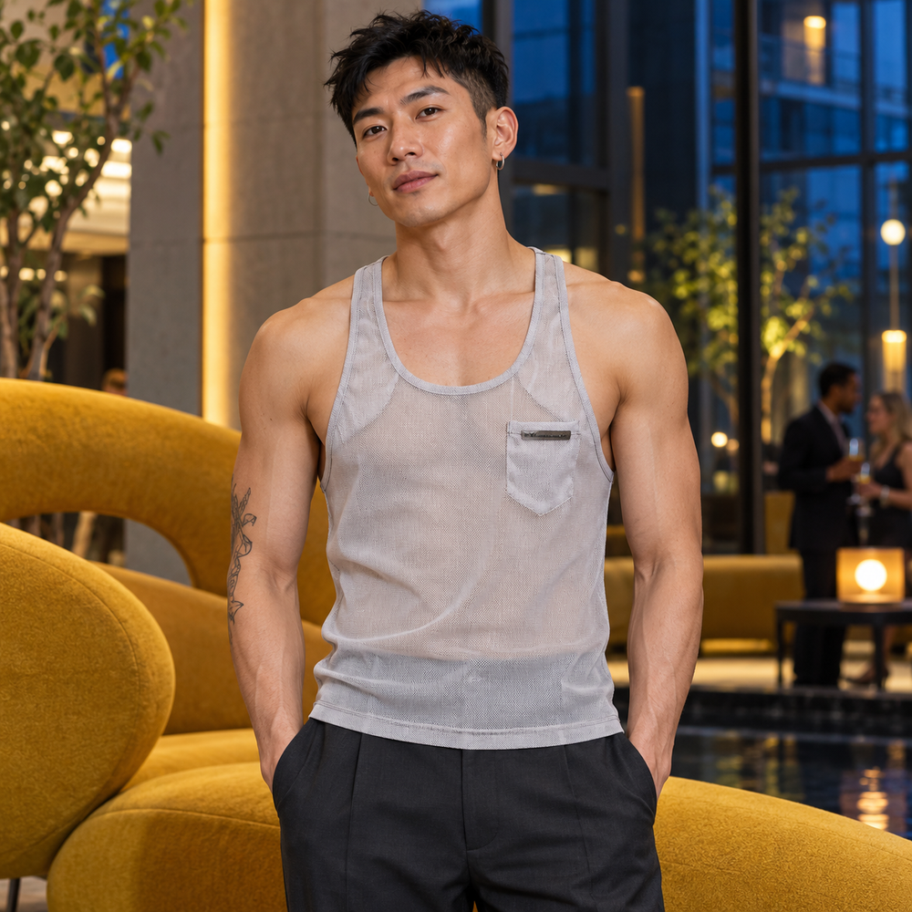 Gym Mesh Tank Top in Gray, worn by an adult model a design-hotel atrium with mustard upholstery and midnight-blue glass.