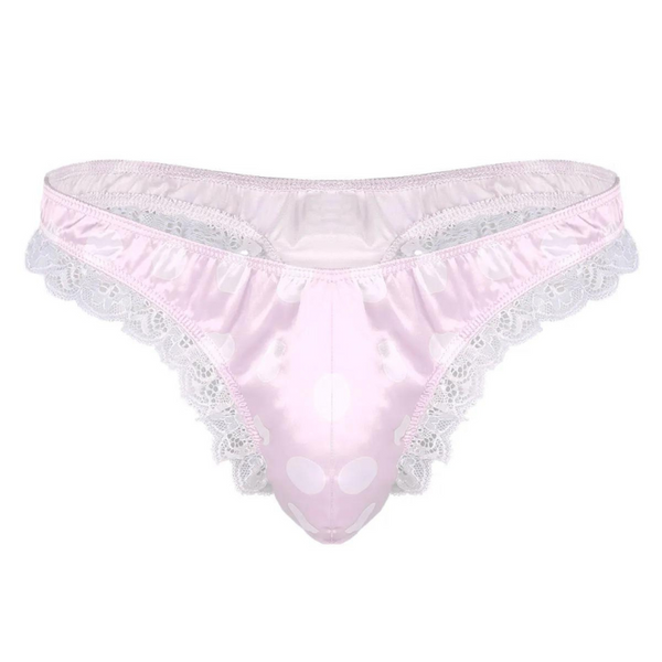 The Crossdressing Shiny Ruffle Lace Polka Thong features light pink satin-like fabric with playful white polka dots and delicate white lace trim, embodying bold queer pride and self-expression.