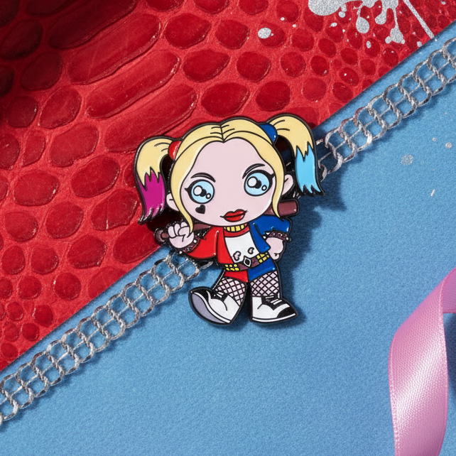 Harley Quinn Enamel Pin featuring a vibrant, chibi-style character with pink-and-blue pigtails, red-and-blue attire, and a playful bat. Celebrating queer pride and self-expression with bold, joyful energy.