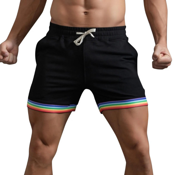Rainbow Sprint Sports Shorts on male model, featuring black fabric and rainbow-striped hem. Designed for queer pride, these shorts celebrate self-expression and empowerment with bold style and comfortable fit.