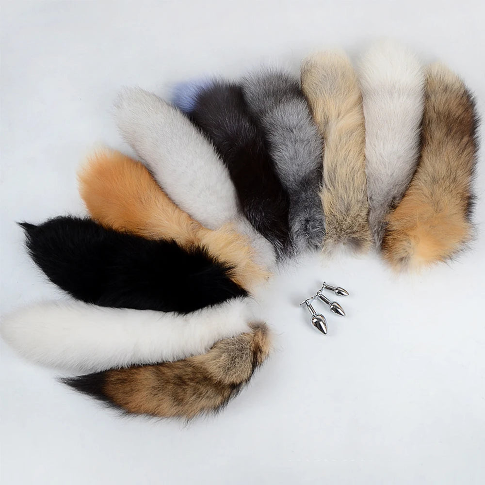 Flat lay of assorted faux-fur fox tails with silver metal butt plug attachments