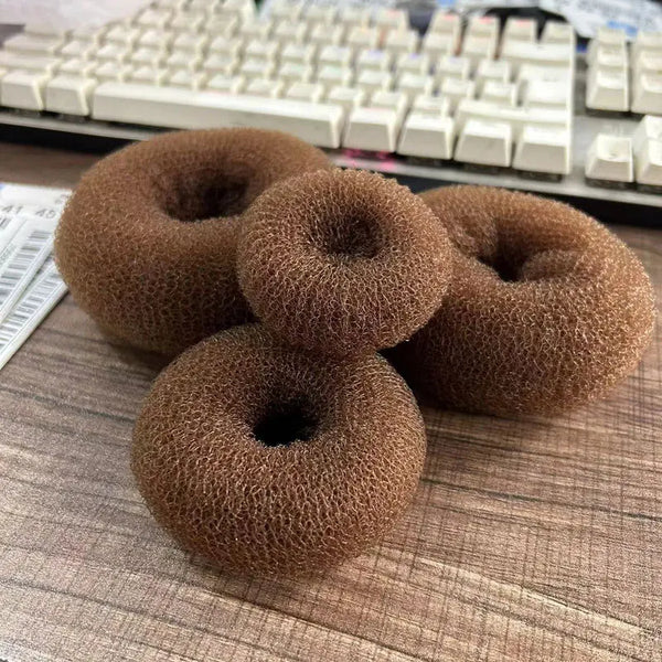 Sky High Stewardess Bun Maker: Four brown foam mesh rings on a wood surface, perfect for crafting sleek, secure buns. Ideal for drag, cosplay, and expressing bold, queer pride with ease and style.