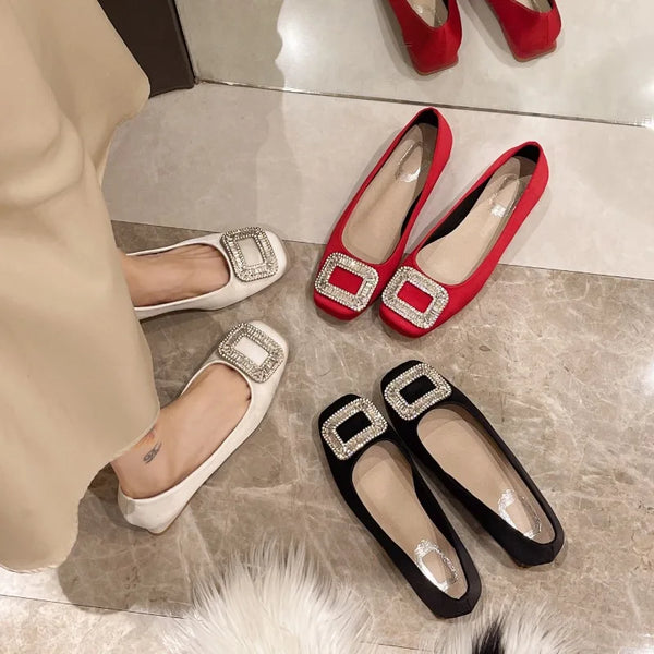 Three pairs of First Class Purser Rhinestone Pumps with square toes and crystal buckles, reflecting queer elegance and empowerment; one pair worn, showcasing inclusivity and self-expression in striking white, red, and black.