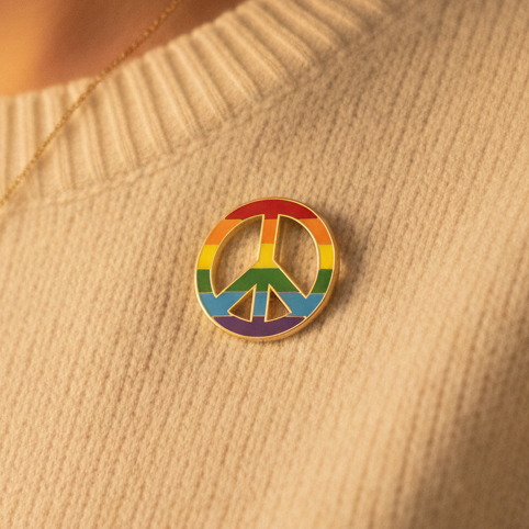 Close-up of the LGBT Peace Enamel Pin attached to a light knit sweater, featuring a rainbow-flag peace symbol, embodying pride, self-expression, and bold queer visibility.