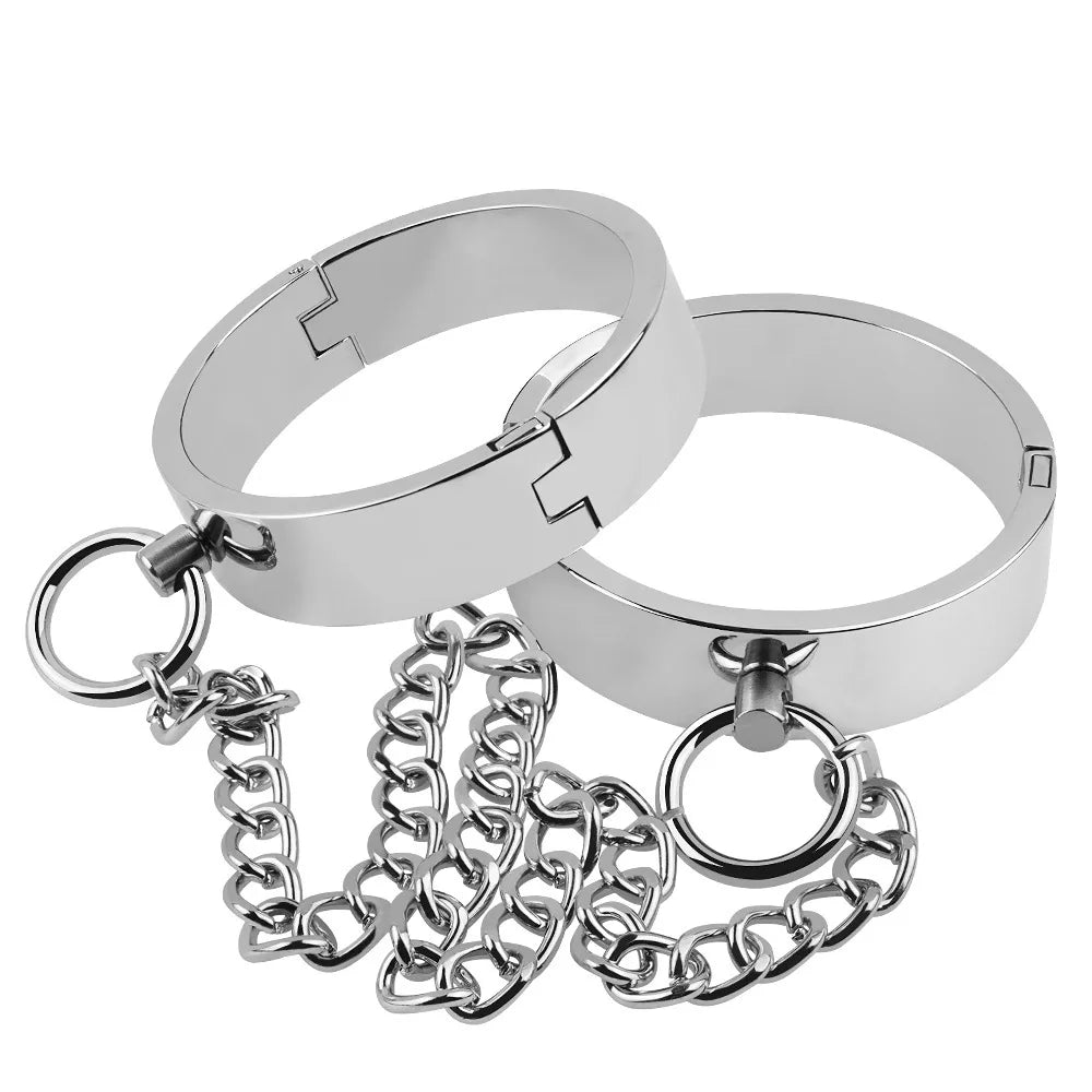Two silver metal bondage cuffs linked by chains and large O-rings on white