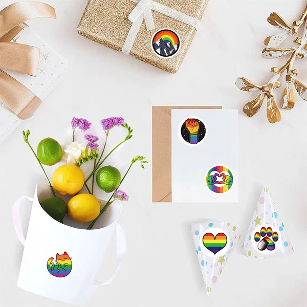 Overhead display of Pride stickers decorating gifts, a card, a bouquet, and party hats