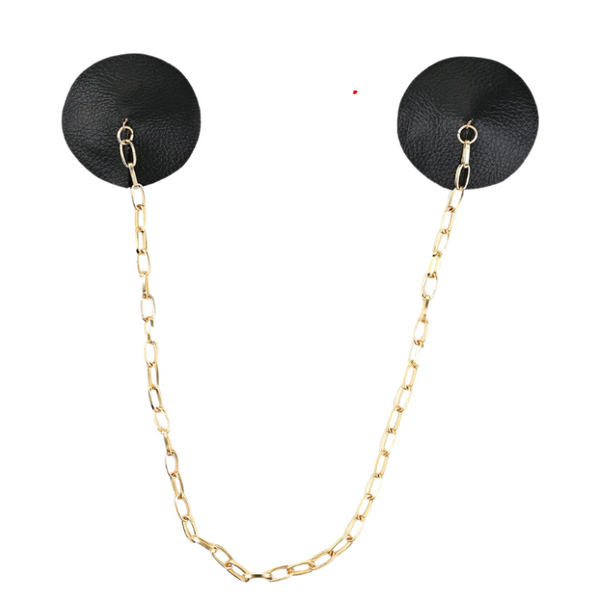 The Tempting Tethered Nipple Covers feature round black synthetic leather-look pasties linked by a gold-tone chain, embodying bold self-expression and empowerment for the vibrant queer community.