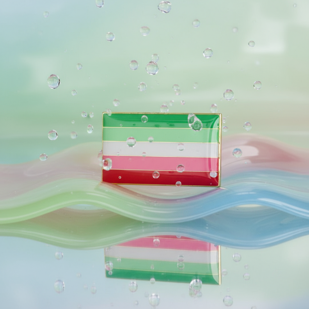 Rectangular abrosexual pride flag enamel pin standing amid pastel waves and water droplets