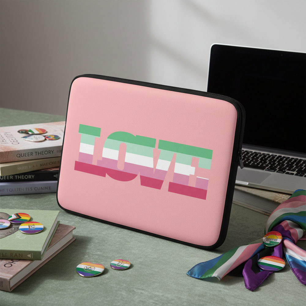 Abrosexual Pride laptop sleeve with bold "LOVE" in pride colors sits on desk amid queer buttons, rainbow scarf, books