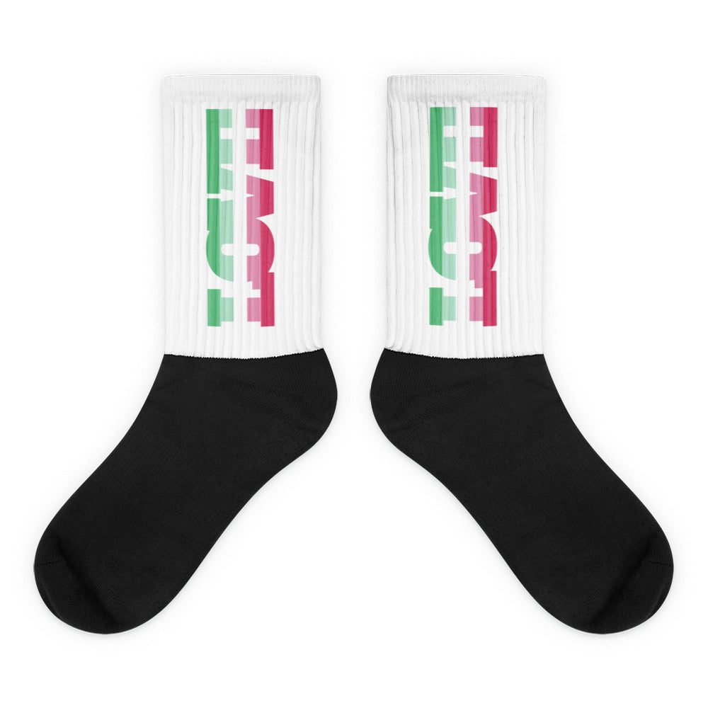 Pair of black-and-white crew socks with green and pink vertical graphics on the cuffs