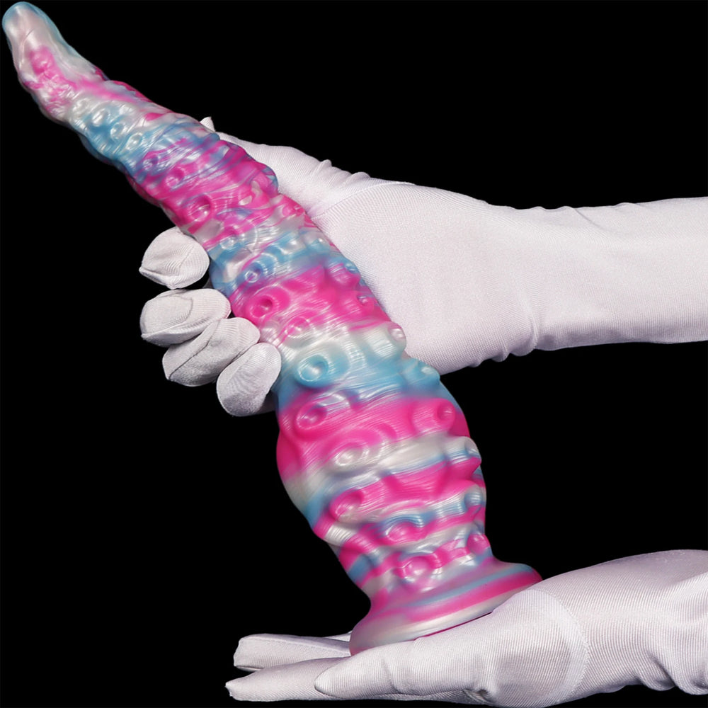 Gloved hands hold a tapered, tentacle-textured anal dildo in translucent pink, blue, and white