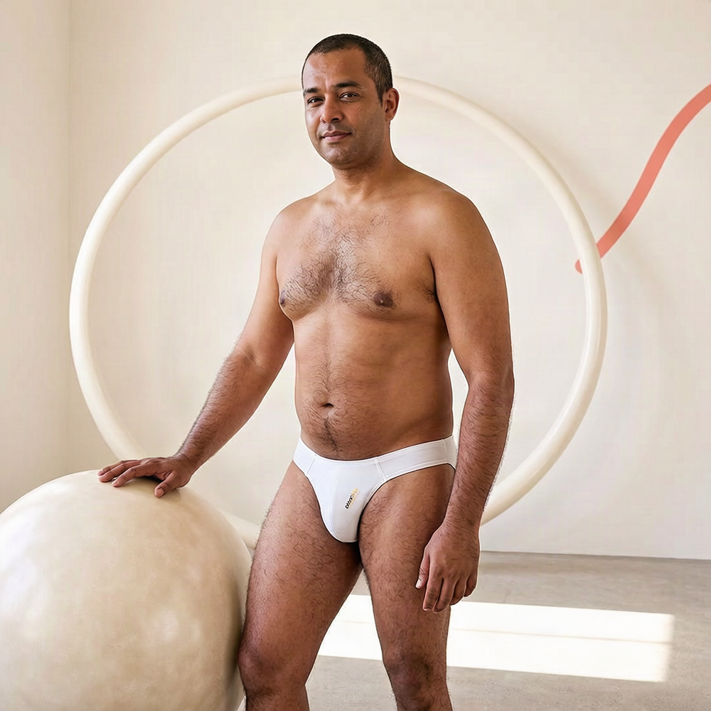 Adult model wearing the white ADANNU Classic Thong in a sculptural ivory studio