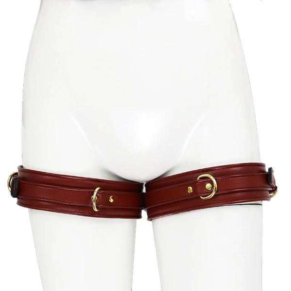 Front view of dark brown leather thigh cuffs with gold buckles on a white mannequin