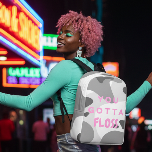 You Gotta Floss Minimalist Backpack with “YOU GOTTA FLOSS” in pink, worn by a queer cutie with pink curls, teal top, and silver skirt.
