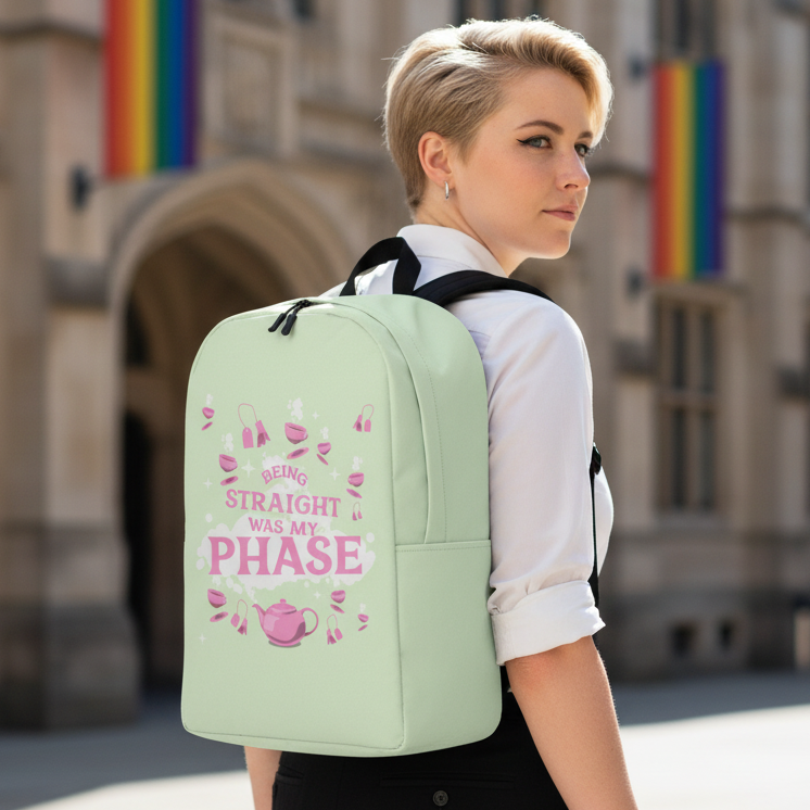 “Being Straight Was My Phase Minimalist Backpack” with pink text, teacup and shoe icons; rainbow flags in the background.