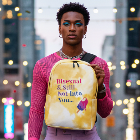 Bisexual & Still Not Into You Minimalist Backpack with popsicle graphic held by queer person in pink mesh top on city street at dusk.