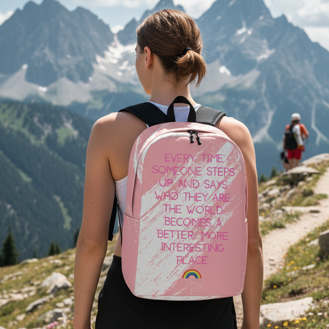 Every Time Someone Steps Up Minimalist Backpack with rainbow design and quote, worn by a woman on a mountain trail.