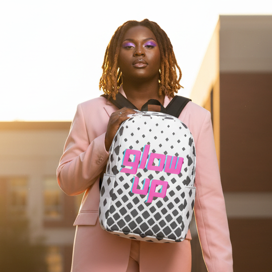 Glow Up Minimalist Backpack with bold pink “glow up” text, carried by a stylish person in a light pink suit at sunset.