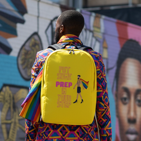 Minimalist backpack reading "Put Some Prep In Your Step" with a rainbow flag, worn over a bright jacket; mural in back.