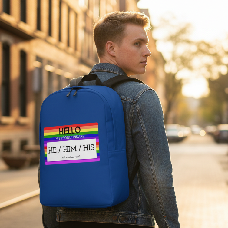 Minimalist backpack in royal blue with a rainbow patch and "Hello My Pronouns Are He / Him / His," worn by a queer man in denim.