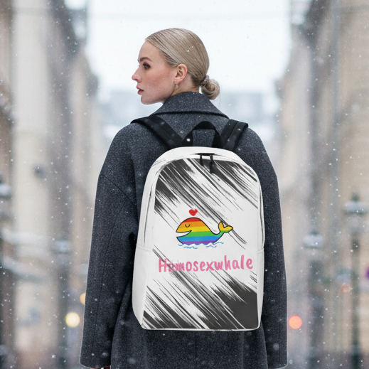 Homosexwhale Minimalist Backpack—a white bag with a rainbow cartoon whale, heart, and "Homosexwhale" in pink—carried by a woman in a dark coat, pops against snowy city streets and radiates queer pride.