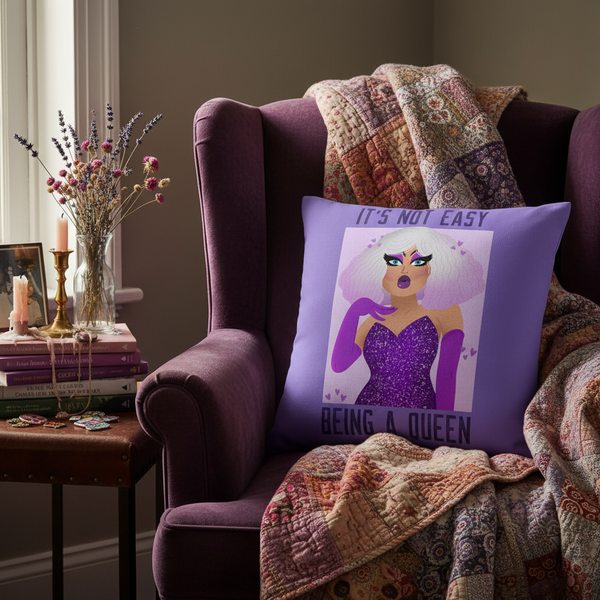 Purple queen graphic pillow reading “IT’S NOT EASY BEING A QUEEN” in a cozy armchair