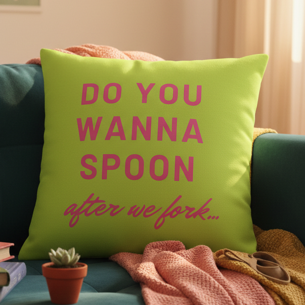 Do You Wanna Spoon After We Fork" pillow with bold pink text, a playful queer vibe, styled with blankets, book, and plant.