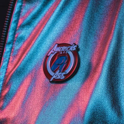 America's Ass enamel pin with red, blue, and black circular design on striped fabric