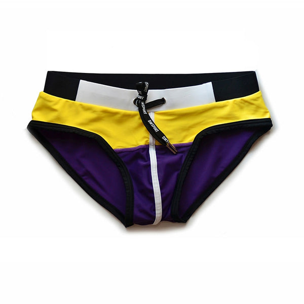 Front view of yellow, purple, black, and white patchwork swim briefs with a drawstring