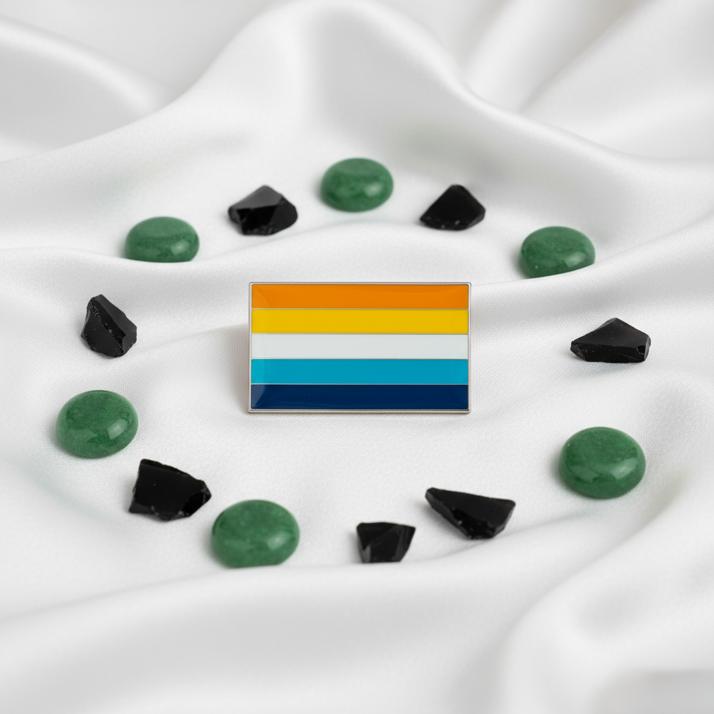 Aroace pride flag enamel pin resting on white satin among green and black stones