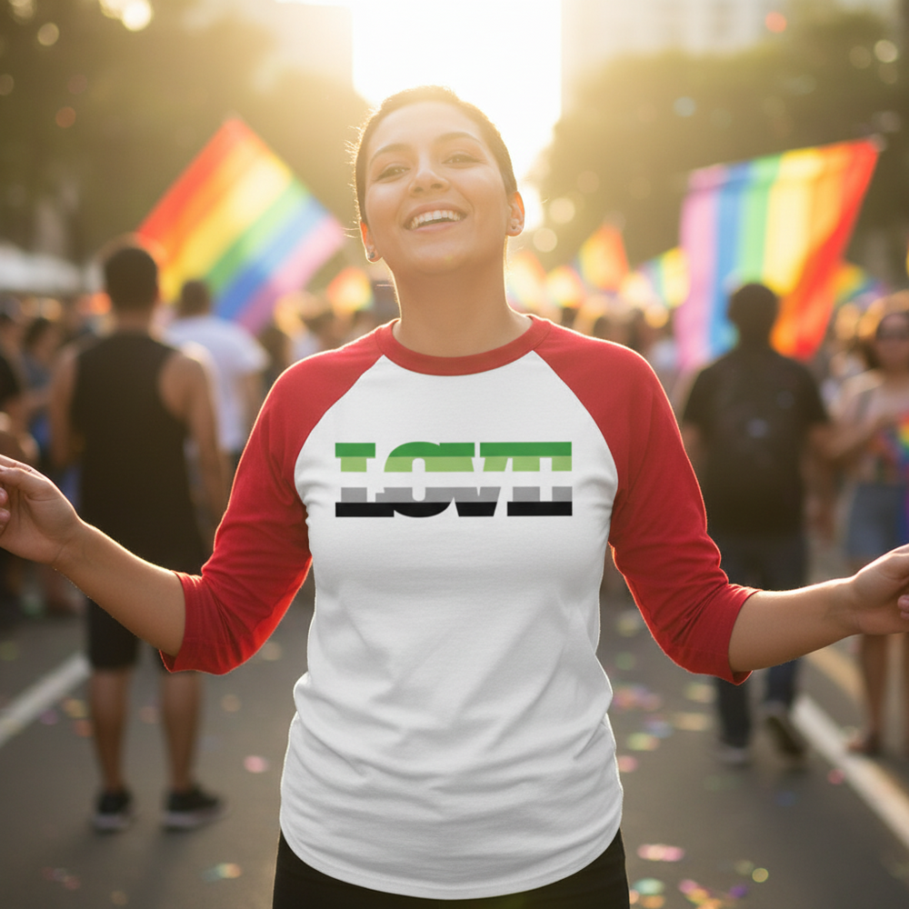 Aromantic Love 3/4 sleeve raglan shirt worn by a smiling person at a sunny queer parade, rainbow flags and people all around.