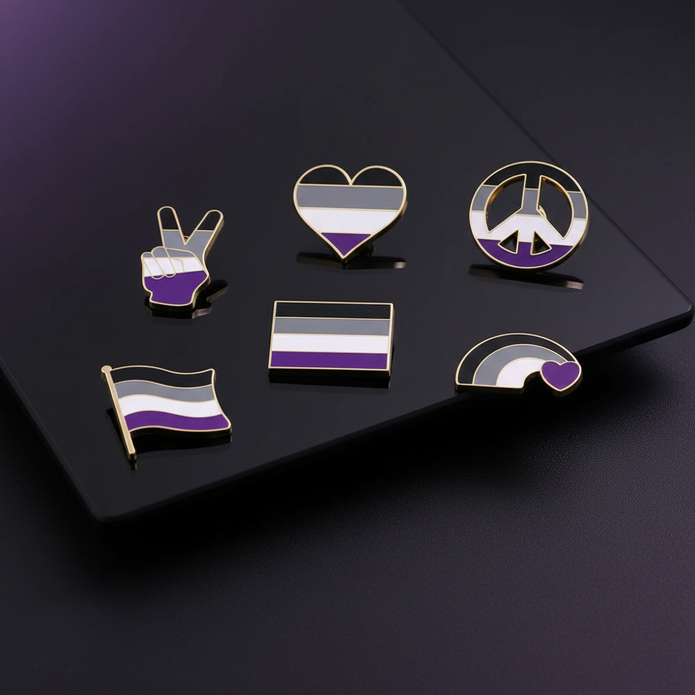Six gold-outlined asexual-pride enamel pins arranged on a black display board