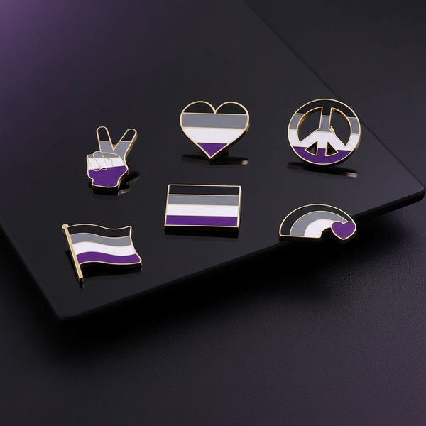 Six gold-outlined asexual-pride enamel pins arranged on a black display board