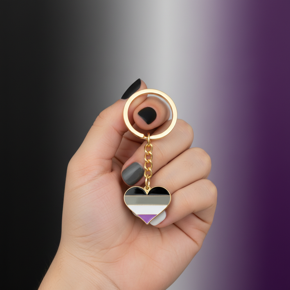 Hand holding an asexual pride heart keychain with black, gray, white, and purple stripes