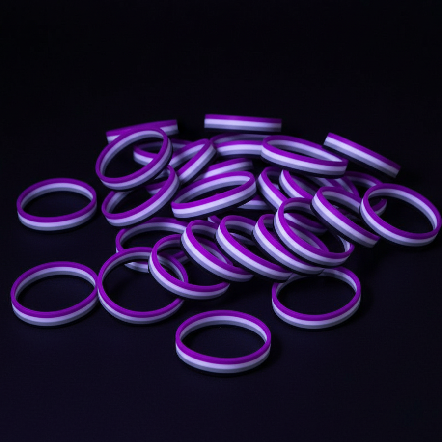 Pile of purple, lavender, and white striped silicone wristbands on a black surface