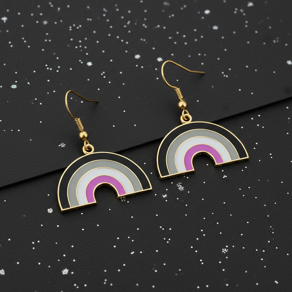 Gold-tone rainbow arch earrings with black, gray, white, and magenta enamel, laid on black speckled fabric