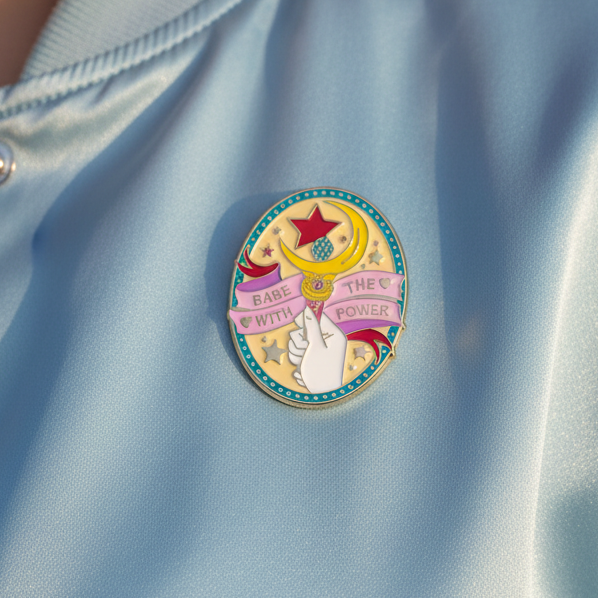 Close-up of a colorful enamel pin reading “Babe With The Power” with a star and raised fist