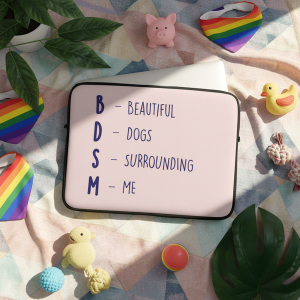 BDSM (Beautiful Dogs Surrounding Me) laptop sleeve on a pastel checkered blanket, with rainbow heart bibs, dog toys, plant