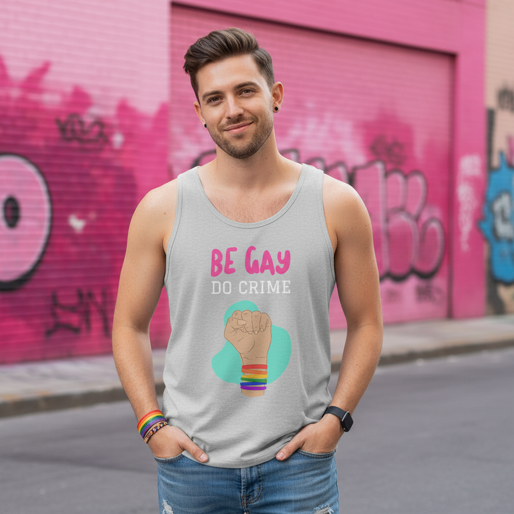 Be Gay Do Crime Unisex Tank Top, jeans, rainbow bracelets; smiling queer man by pink graffiti wall, Pride-ready energy.