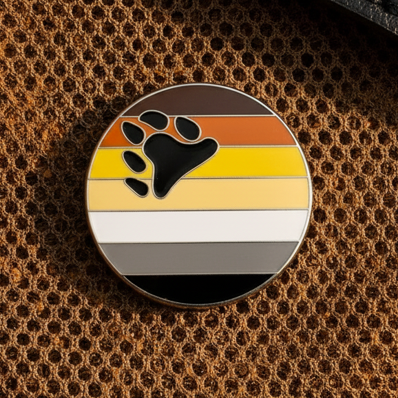 Bear pride enamel pin with black paw print over brown, orange, yellow, cream, gray, and black stripes