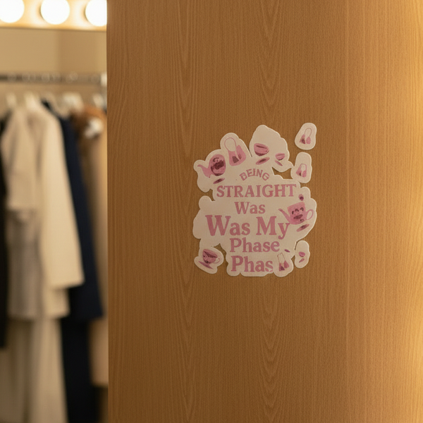Being Straight Was My Phase bubble-free sticker with pink text and lipstick marks on light wood; queer clothes