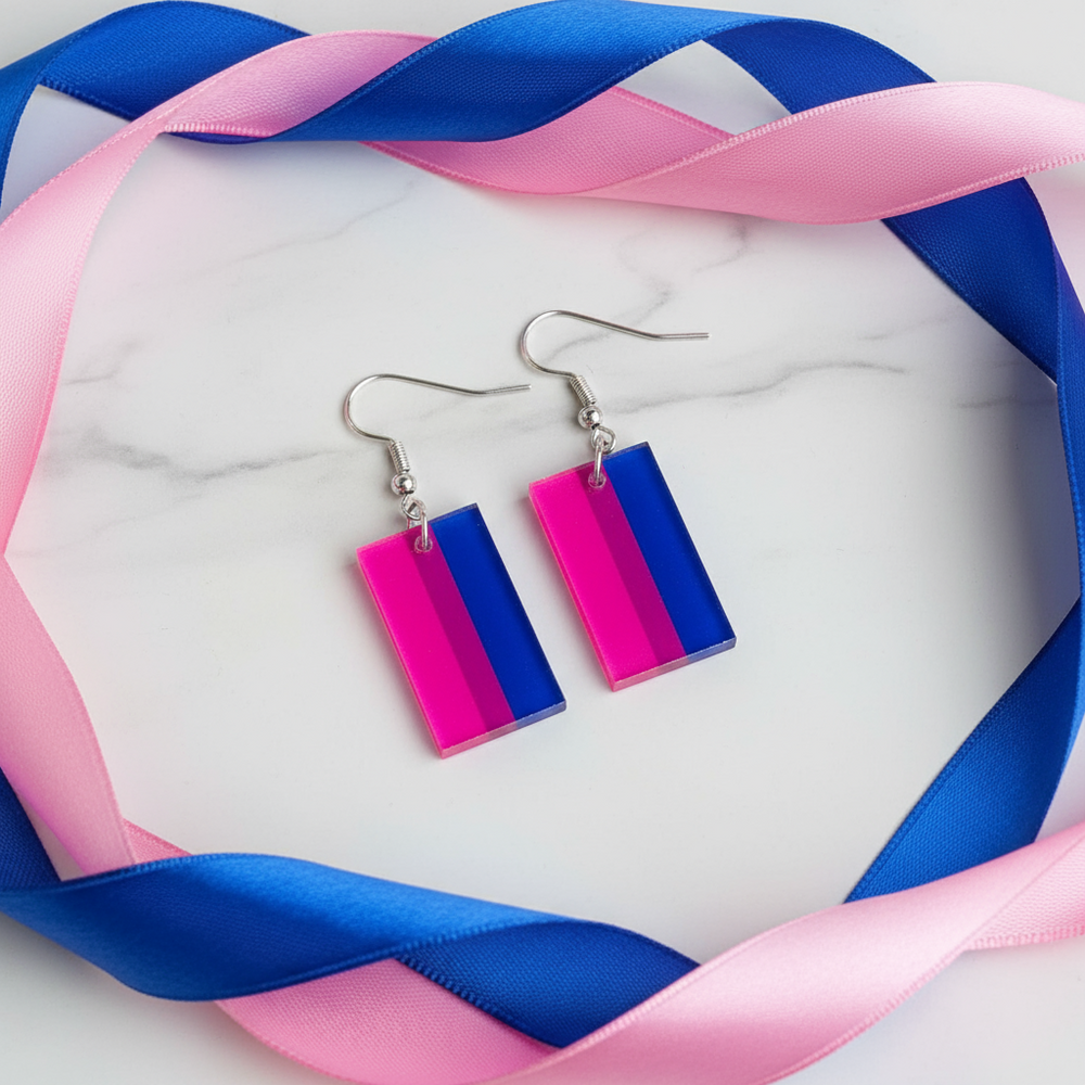 Pair of pink and blue rectangular acrylic dangle earrings on a marble-effect surface
