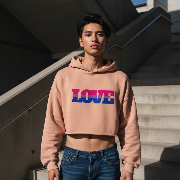 Bisexual Love Crop Hoodie, peach with “LOVE” in bi flag blue, pink, and purple; worn outdoors by stairs, repping queer style.