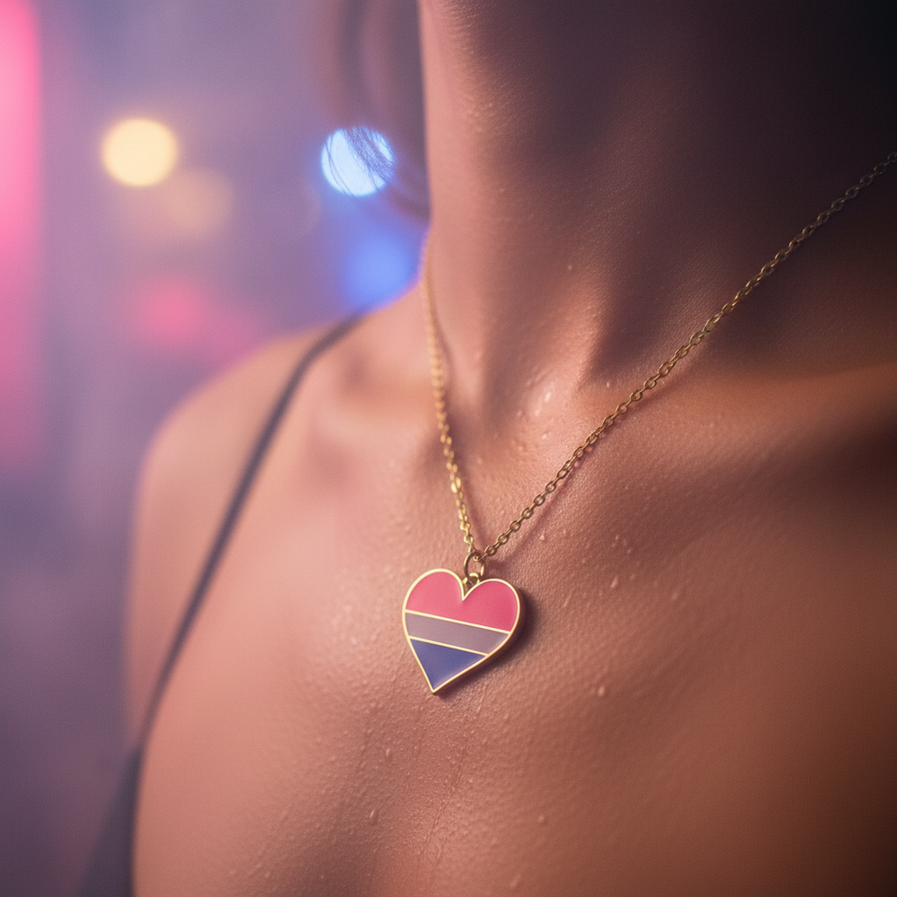 Gold-tone chain with a heart pendant in pink, purple, and blue stripes on a model's chest