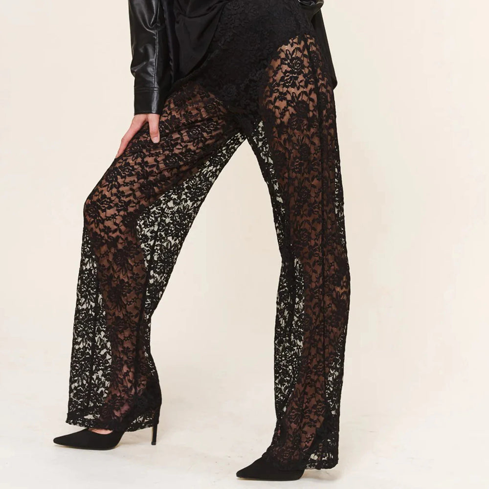 Close-up model view of black floral lace trousers with wide flared legs