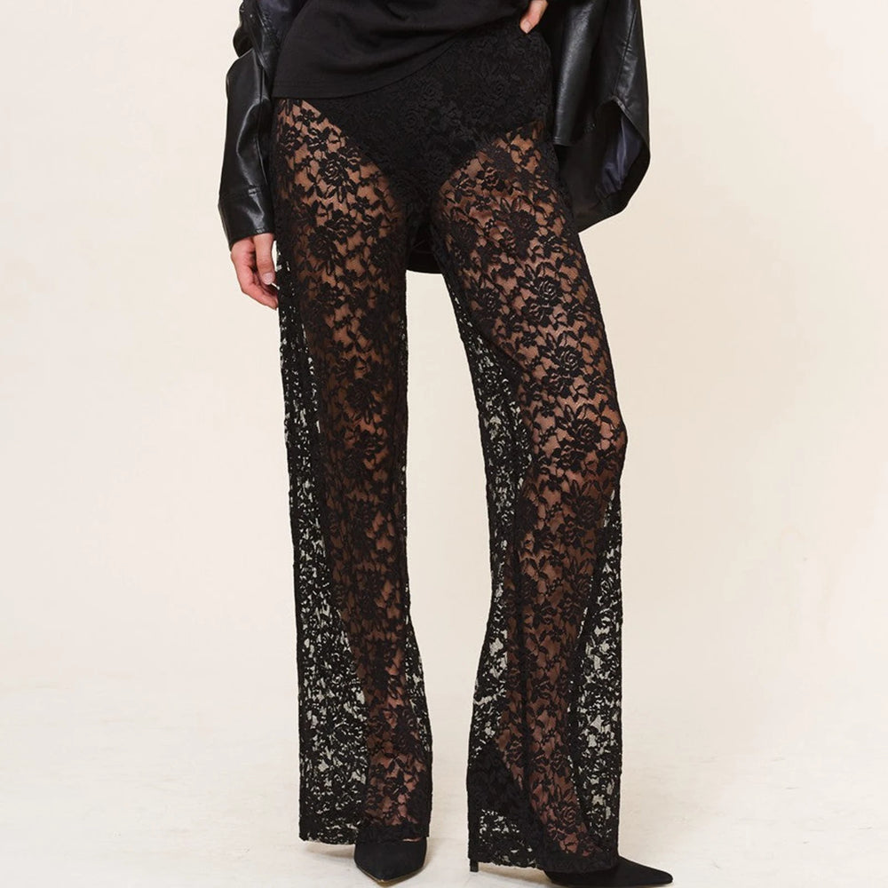 Front view of a model wearing black sheer floral lace trousers with flared legs